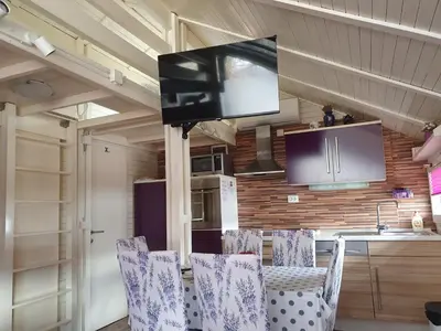 a kitchen with chairs and a flat screen tv at Spa Cottage Lavender in Terme Čatež in Čatež ob Savi