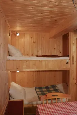 two bunk beds in a wooden cabin with a table at Chalet Kočna - I FEEL ALPS in Stahovica