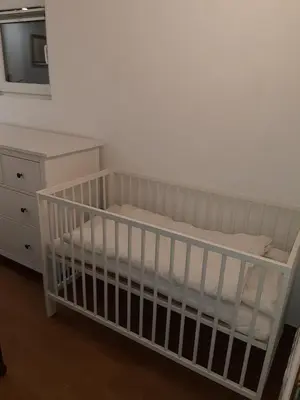 a white crib in a room with a dresser at Apartment by Tanja&Nejc in Bled