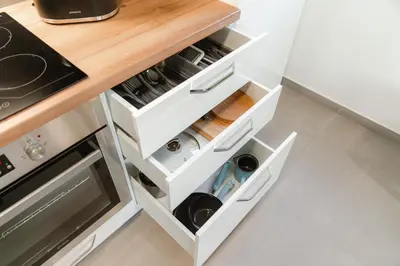 a kitchen with white drawers with wine bottles at Apartma BoLeRo in Tolmin