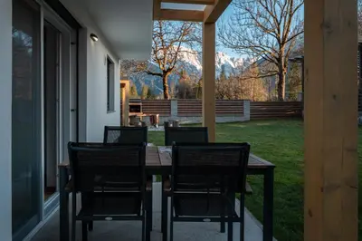 a table and chairs on a porch with a view of a yard at Apartmaji ENIA Rateče-Planica, Kranjska Gora in Kranjska Gora