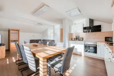 a kitchen and dining room with a wooden table and chairs at Apartmaji ENIA Rateče-Planica, Kranjska Gora in Kranjska Gora