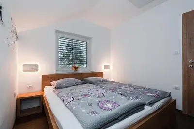 a bedroom with a bed with a blanket on it at Apartmaji ENIA Rateče-Planica, Kranjska Gora in Kranjska Gora