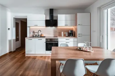 a kitchen with a wooden table and white cabinets at Apartmaji ENIA Rateče-Planica, Kranjska Gora in Kranjska Gora