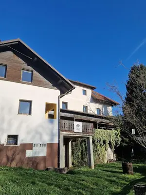 a large white house with a deck on a yard at Krka River Lodge in Krka