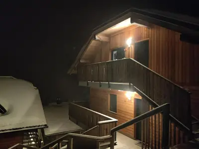 a wooden cabin with a staircase at night at Apartma A1 GOLTE in Mozirska Koča