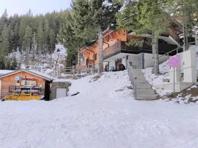 a ski lodge in the snow next to a building at Apartma A1 GOLTE in Mozirska Koča