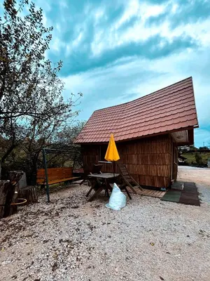 a wooden hut with a table and a yellow umbrella at Koča Janka in Metke in Velika Loka