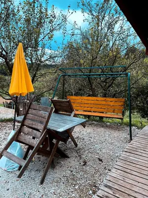 a bench and a picnic table and an umbrella at Koča Janka in Metke in Velika Loka
