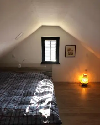 a attic bedroom with a bed and a window at Adorable guesthouse in the middle of vineyards in Ptujska Gora