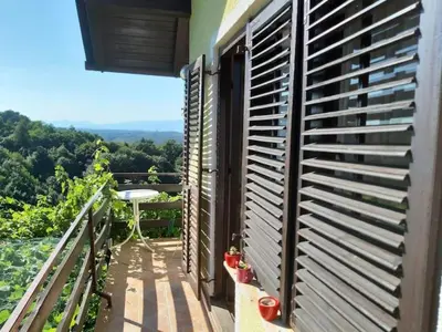 a balcony with shutters on the side of a house at Adorable guesthouse in the middle of vineyards in Ptujska Gora