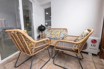 two wicker chairs and a table on a porch at Rakita Premium Family Suite in Moravske Toplice