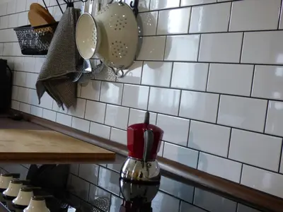 a kitchen with white tiles on a wall with utensils at Hisa STERNA - WELL HOUSE in Zgornje Škofije