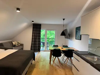 a bedroom with a bed and a kitchen with a table at Apartmaji Kotnik in Kranjska Gora