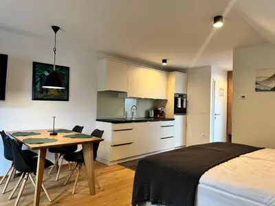 a bedroom with a bed and a table and a kitchen at Apartmaji Kotnik in Kranjska Gora