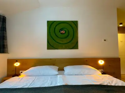 a bedroom with a bed with two pillows and a painting at Apartmaji Kotnik in Kranjska Gora