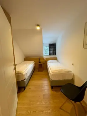 a room with two beds and a chair in it at Apartmaji Kotnik in Kranjska Gora