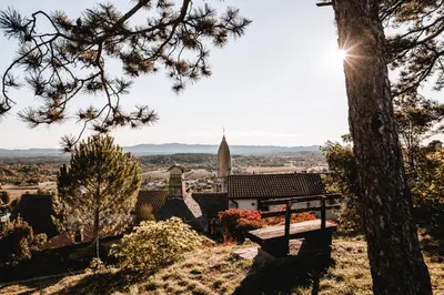 a view of a church from a hill with a bench at Vila Ana in Štanjel