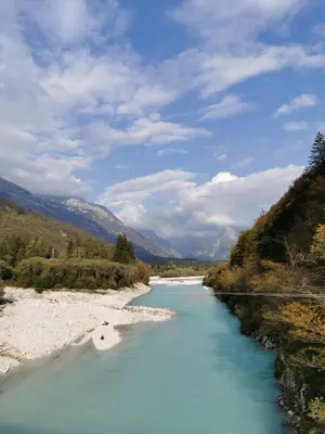 a river with blue water and mountains in the background at APARTMA KAAN in Žaga