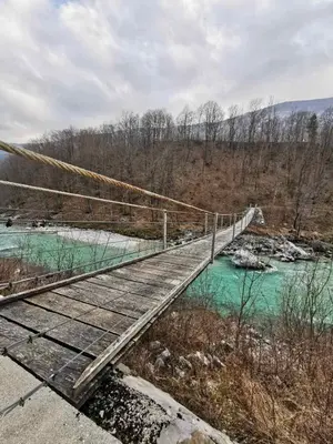 a suspension bridge over a river with blue water at APARTMA KAAN in Žaga