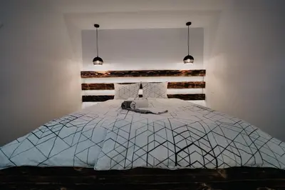 a bedroom with a white bed with two pendant lights at Koča Žafran - Velika planina in Stahovica