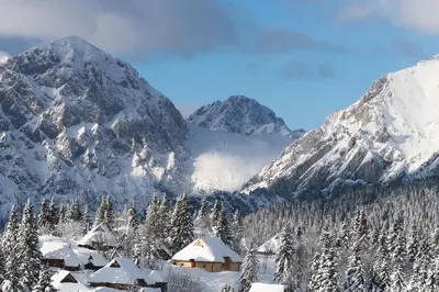 a ski lodge in the mountains with snow covered mountains at Koča Žafran - Velika planina in Stahovica