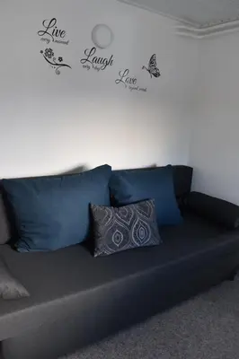 a couch with blue pillows in a living room at Apartma VRBA Dobrna in Dobrna