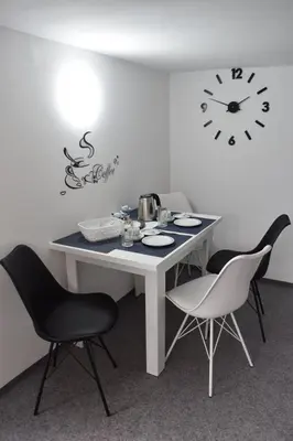 a table with two chairs and a clock on the wall at Apartma VRBA Dobrna in Dobrna
