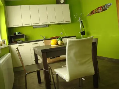 a kitchen with green walls and a table and chairs at Oriana Studios in Bled