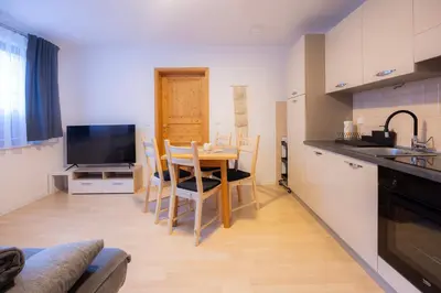 a kitchen with a table with chairs and a television at Apartmaji Anže Kranjska Gora in Kranjska Gora