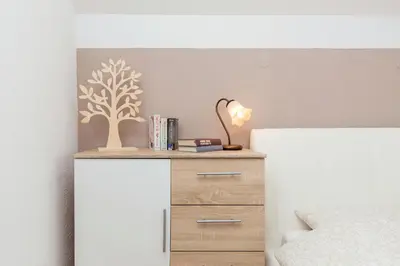 a bedroom with a nightstand with a tree stencil on the wall at Hiša nasproti sonca in Kranjska Gora