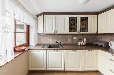 a kitchen with white cabinets and a sink and a window at Hiša nasproti sonca in Kranjska Gora