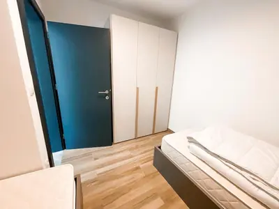 a small room with a bed and a blue door at Sunshine Apartments Golte COMFORT in Mozirje