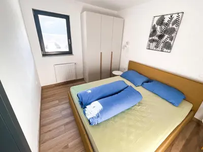 a small bedroom with a bed with blue pillows at Sunshine Apartments Golte COMFORT in Mozirje