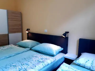 a bed with blue sheets and pillows in a room at SočaLand Apartmaji in Soča
