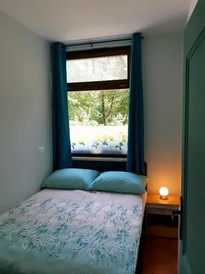 a bedroom with a bed and a window with blue curtains at SočaLand Apartmaji in Soča