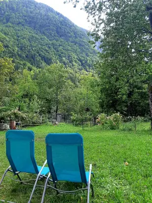 two blue chairs sitting in the grass in a field at SočaLand Apartmaji in Soča