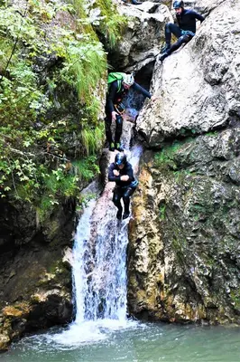 a group of people standing in front of a waterfall at SočaLand Apartmaji in Soča