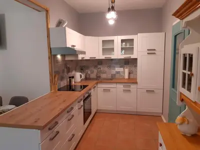 a kitchen with white cabinets and a wooden counter top at SočaLand Apartmaji in Soča