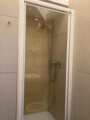 a shower with a glass door in a bathroom at Tiny Twix room in the City centre in Ljubljana