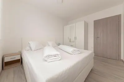 a white bedroom with white sheets and towels on a bed at Perfect Place Apartments in Kranj