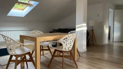 a dining room with a wooden table and white chairs at All Seasons Apartments Laško in Laško