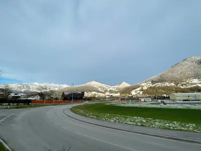 an empty road with snowy mountains in the background at All Seasons Apartments Laško in Laško