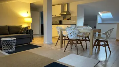 a kitchen and a living room with a table and chairs at All Seasons Apartments Laško in Laško