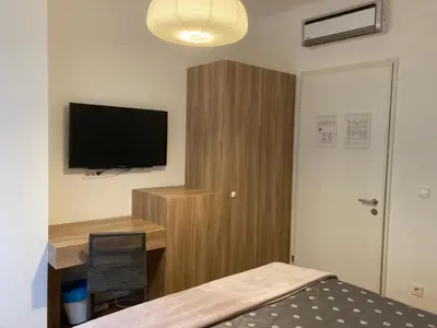 a bedroom with a bed and a desk with a television at Twix rooms in Ljubljana