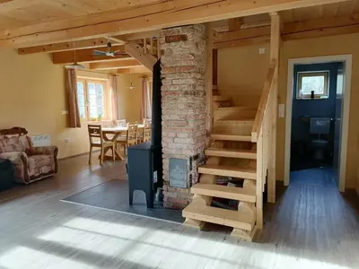 a living room with a staircase and a fireplace at Cottage Golenovo in Podvelka