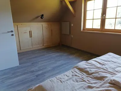 an empty bedroom with a bed and a window at Cottage Golenovo in Podvelka