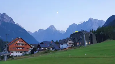 a village on a hill with mountains in the background at Apartments Seventy Seven in Kranjska Gora