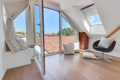 a room with a chair and large windows at Fine Ljubljana Apartments in Ljubljana