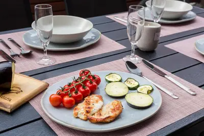 a table with a plate of food with tomatoes and cucumbers at Apartment Lakeside Cerknica in Cerknica
